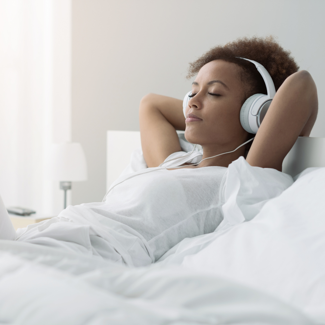 Tinnitus Awareness Day Woman relaxing back on a bed listening to music with over the ear headphones